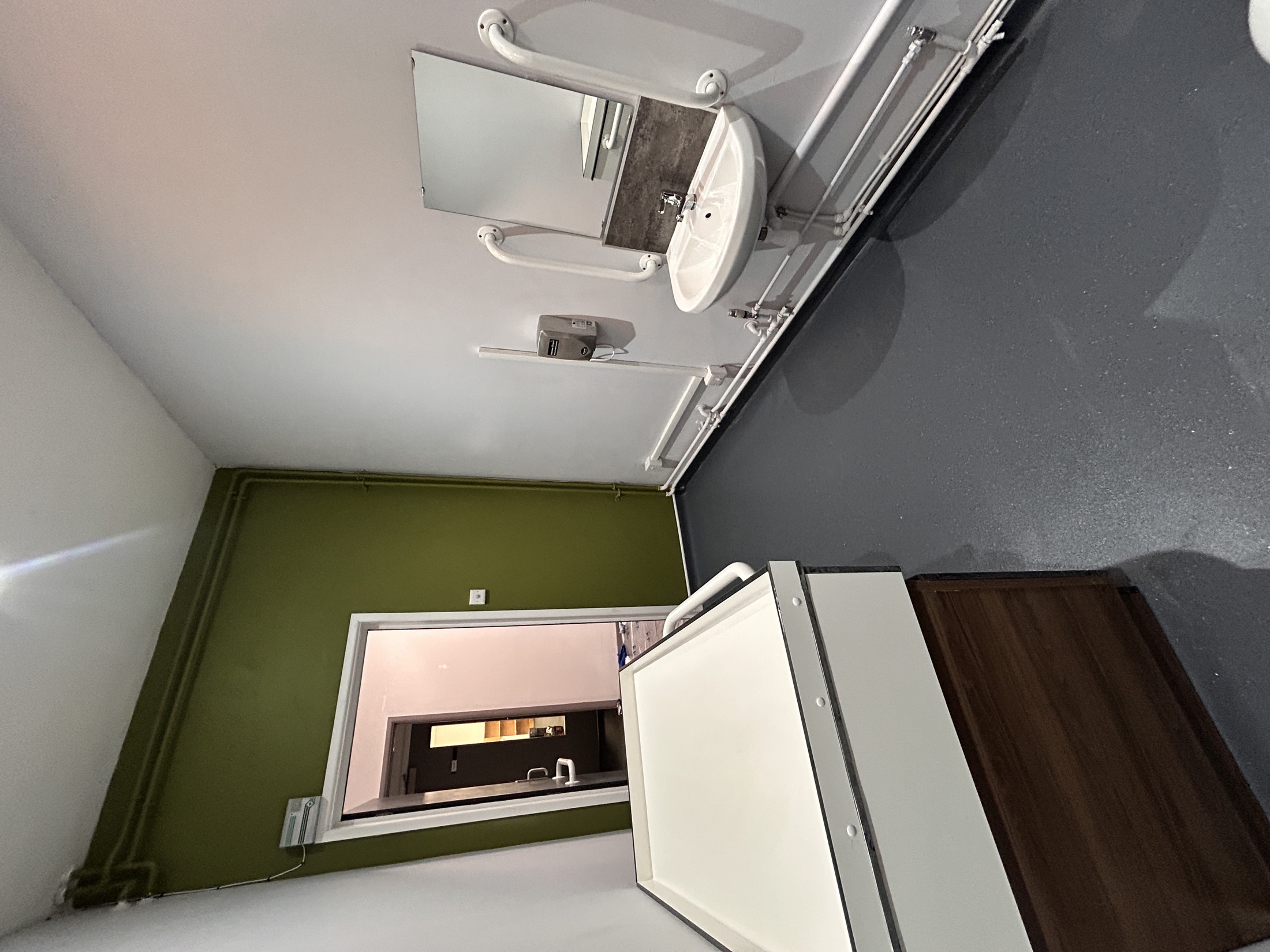 Accessible washroom showing a basin, grab rails, changing surface and clear floor space.