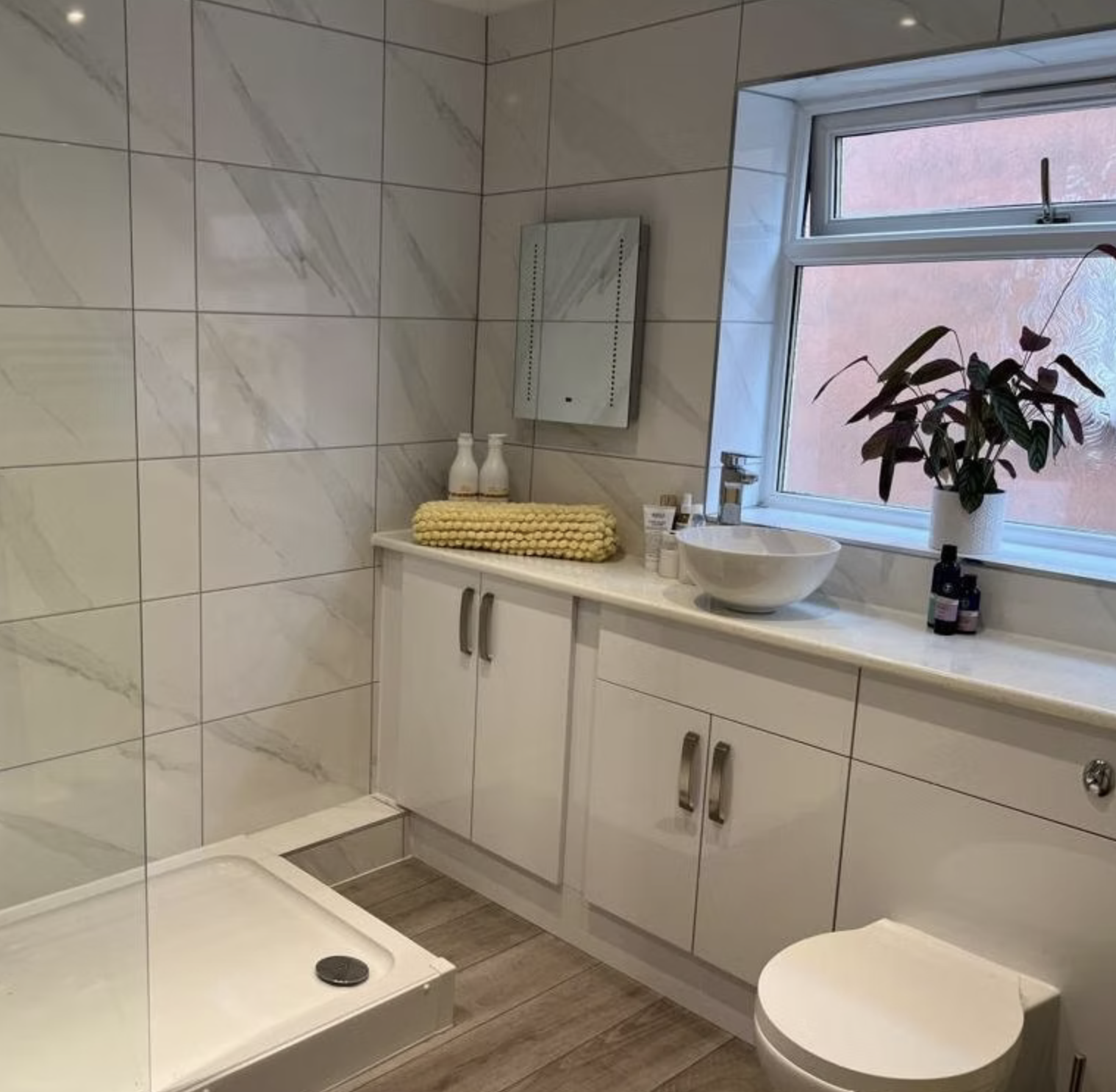 A refined marble-effect bathroom with a fitted vanity beneath the window.