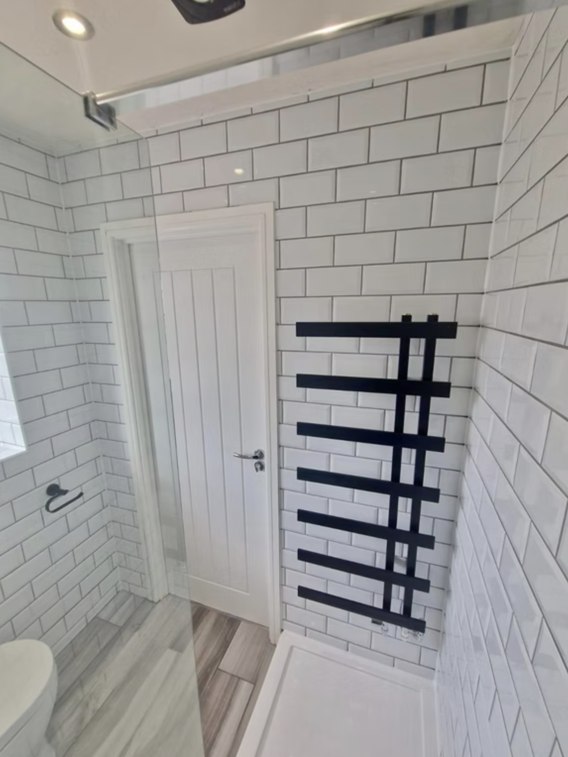 A shower room in white metro tiles with a navy vanity, patterned floor and clear glass screen.
