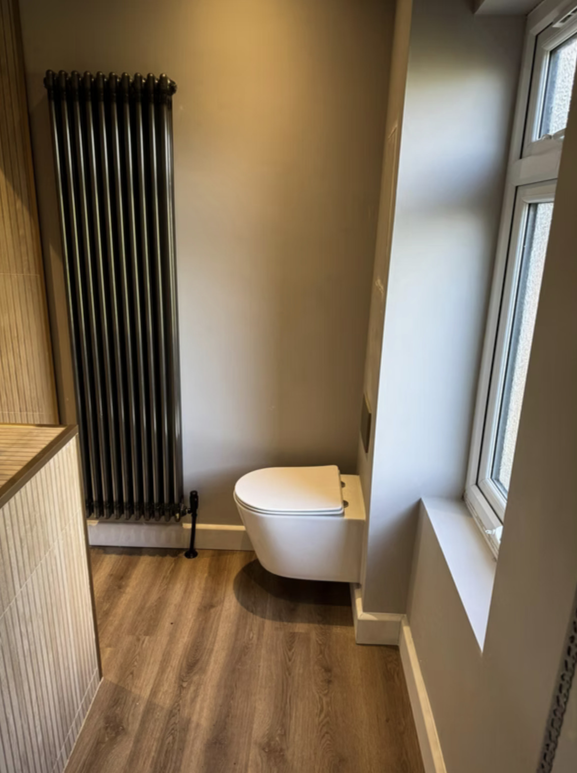 A wall-hung WC and slatted timber-effect wall with a recessed shelf.