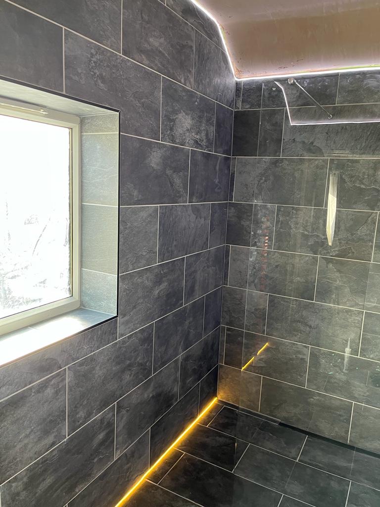 The tiled window reveal, frameless shower screen and illuminated level floor of the wet room.